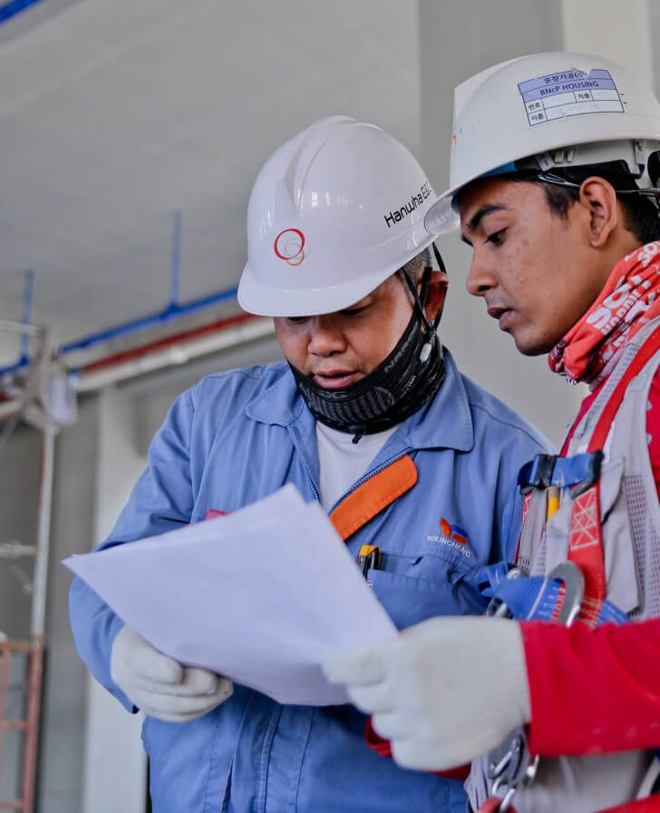 Two construction workers looking at a paper