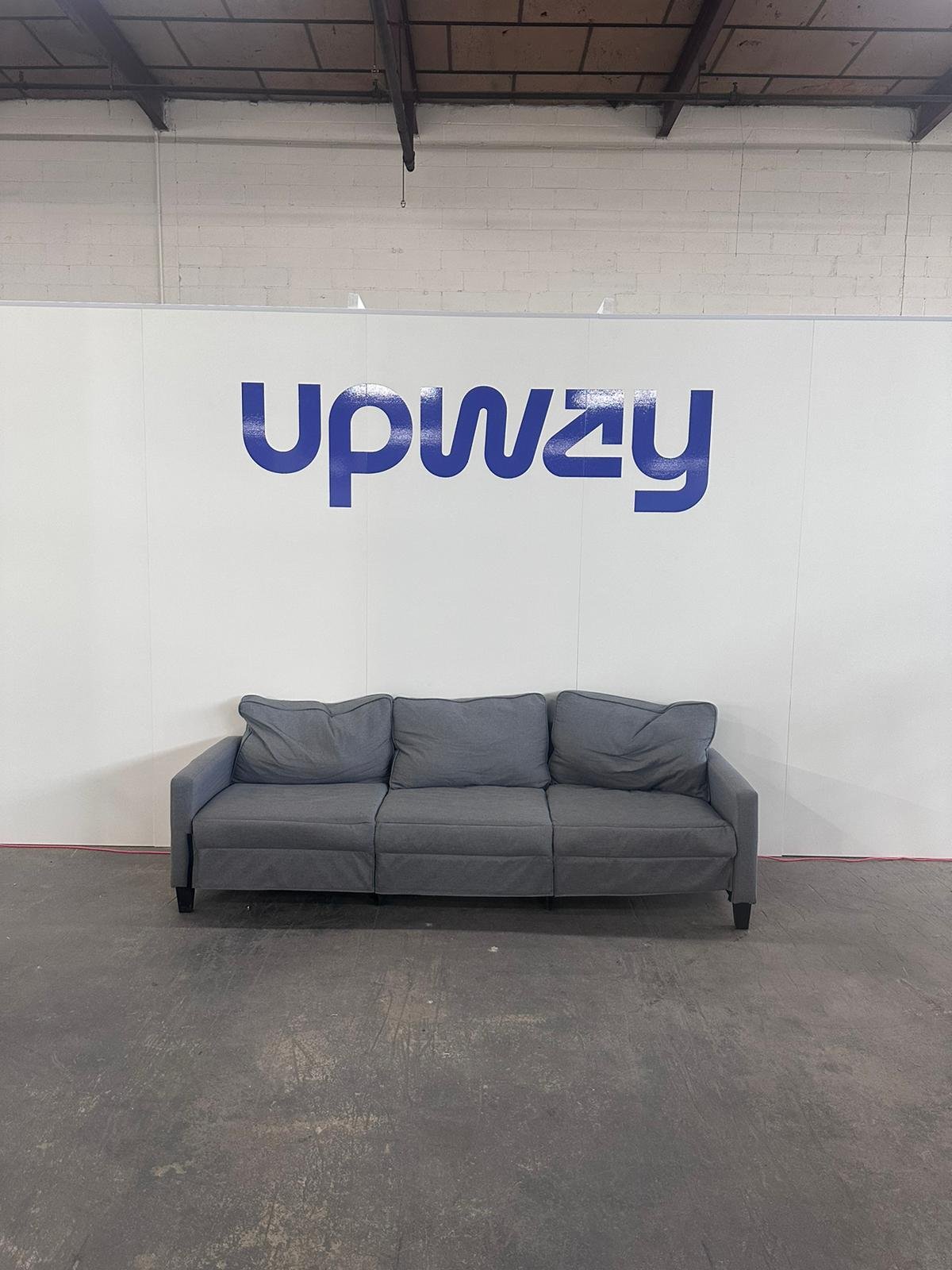 A couch in front of a wall with the word " upway ".