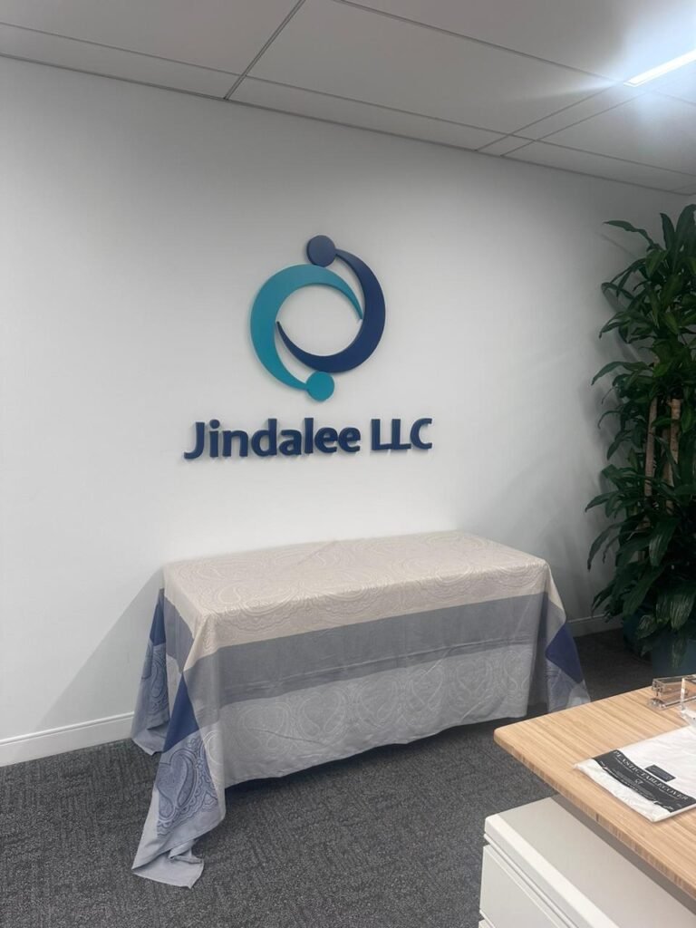 18 - MMK Custom Inc. A table and chairs in front of the jindalee llc logo.