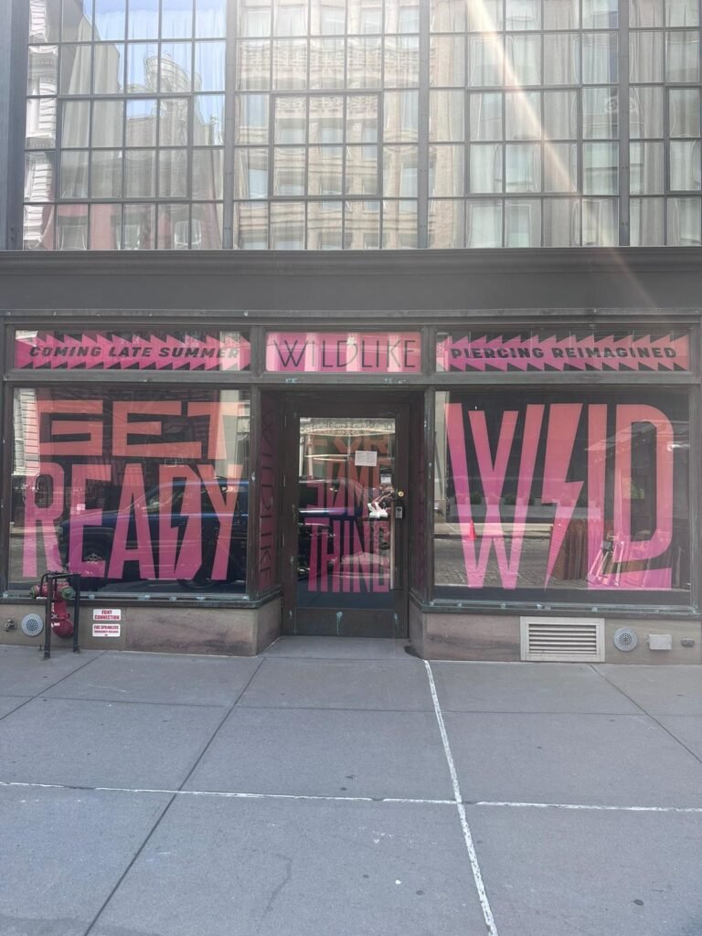 A store front with pink lettering on the windows.