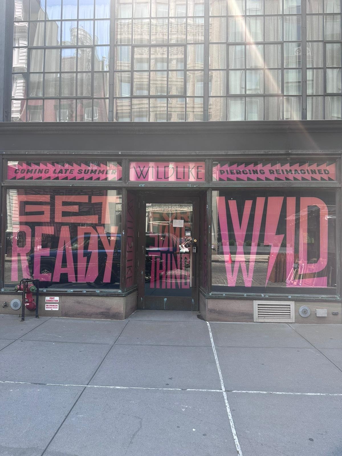 A store front with pink lettering on the windows.