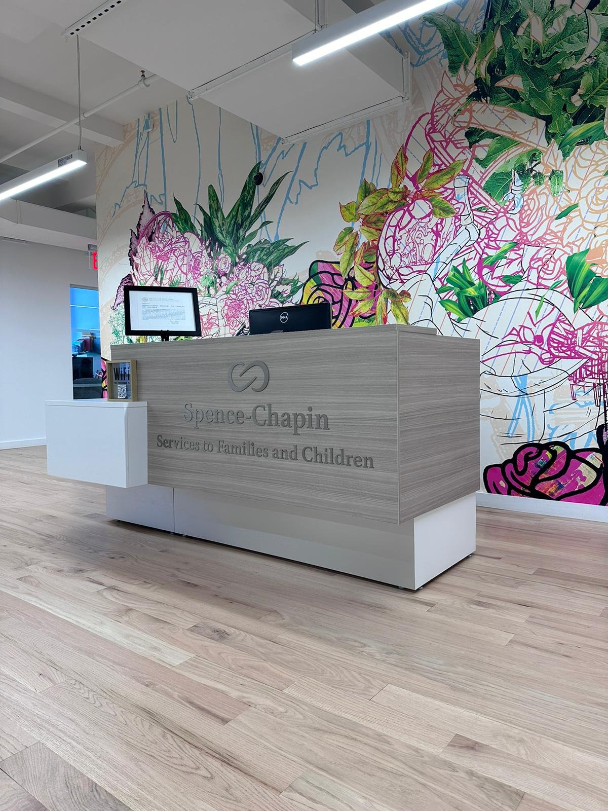 A reception desk with a large floral wall behind it.
