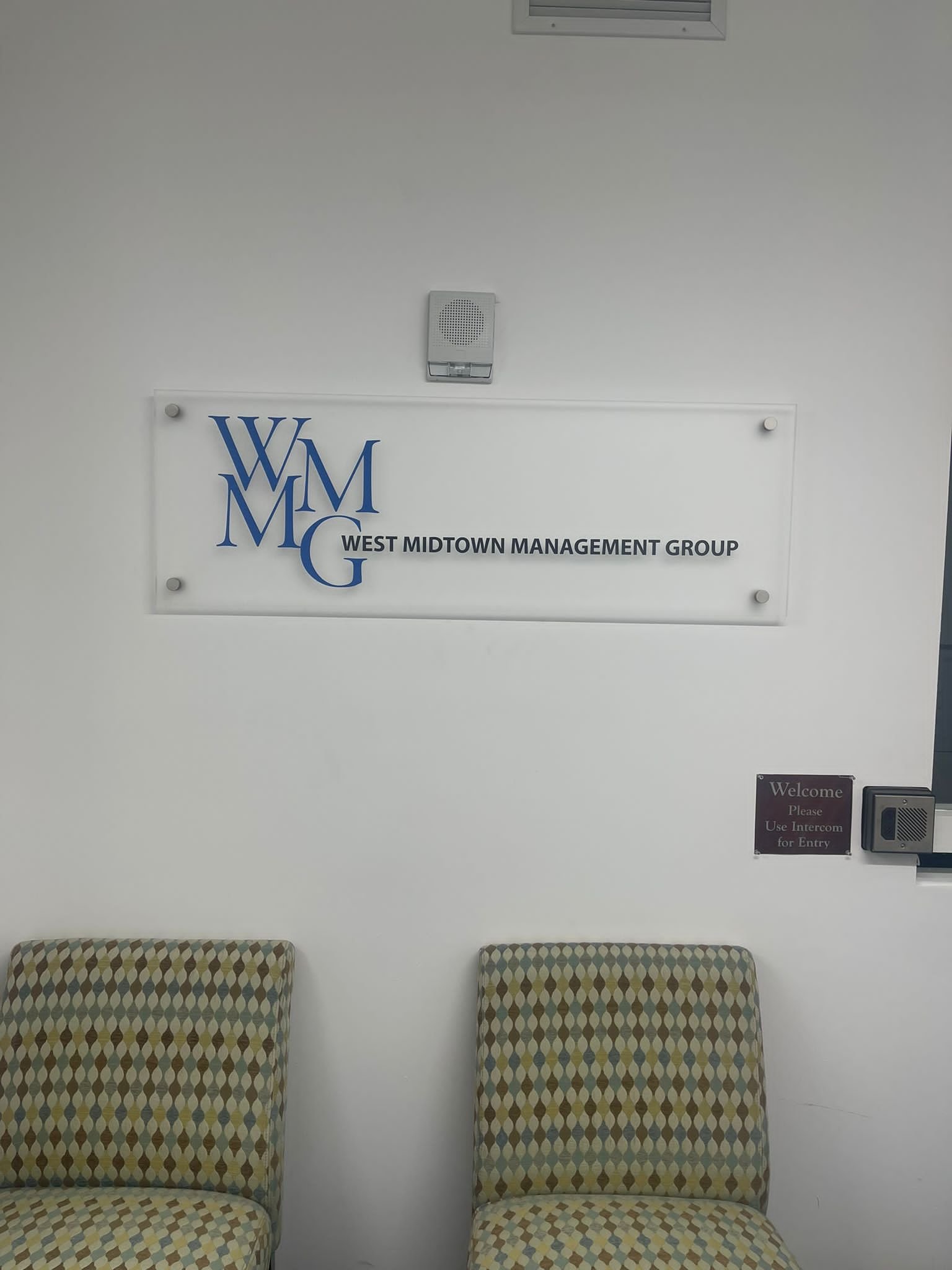 A sign hanging on the wall above two chairs.