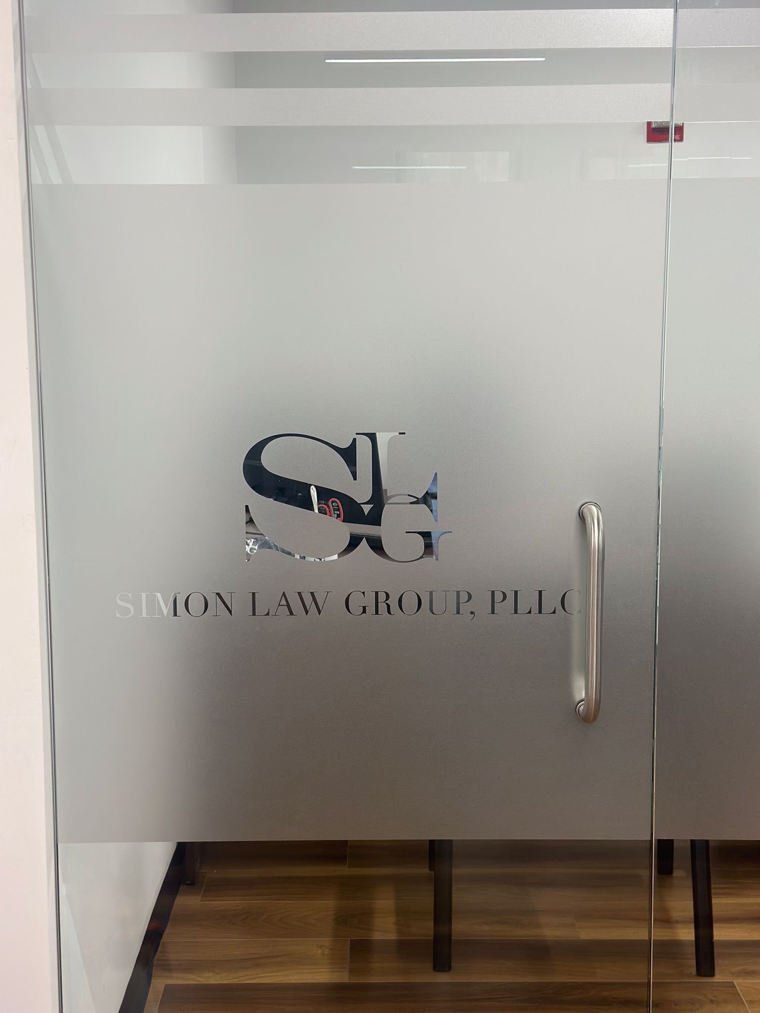 A glass door with the words " jon law group pella."