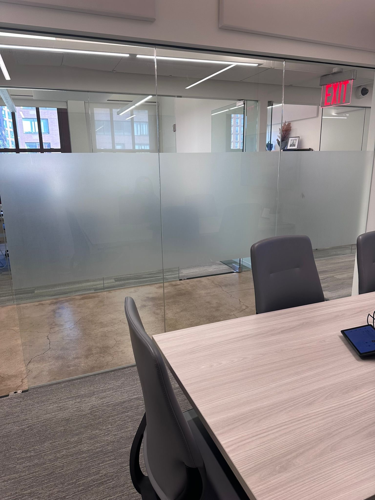 A table and chairs in an office with glass walls.